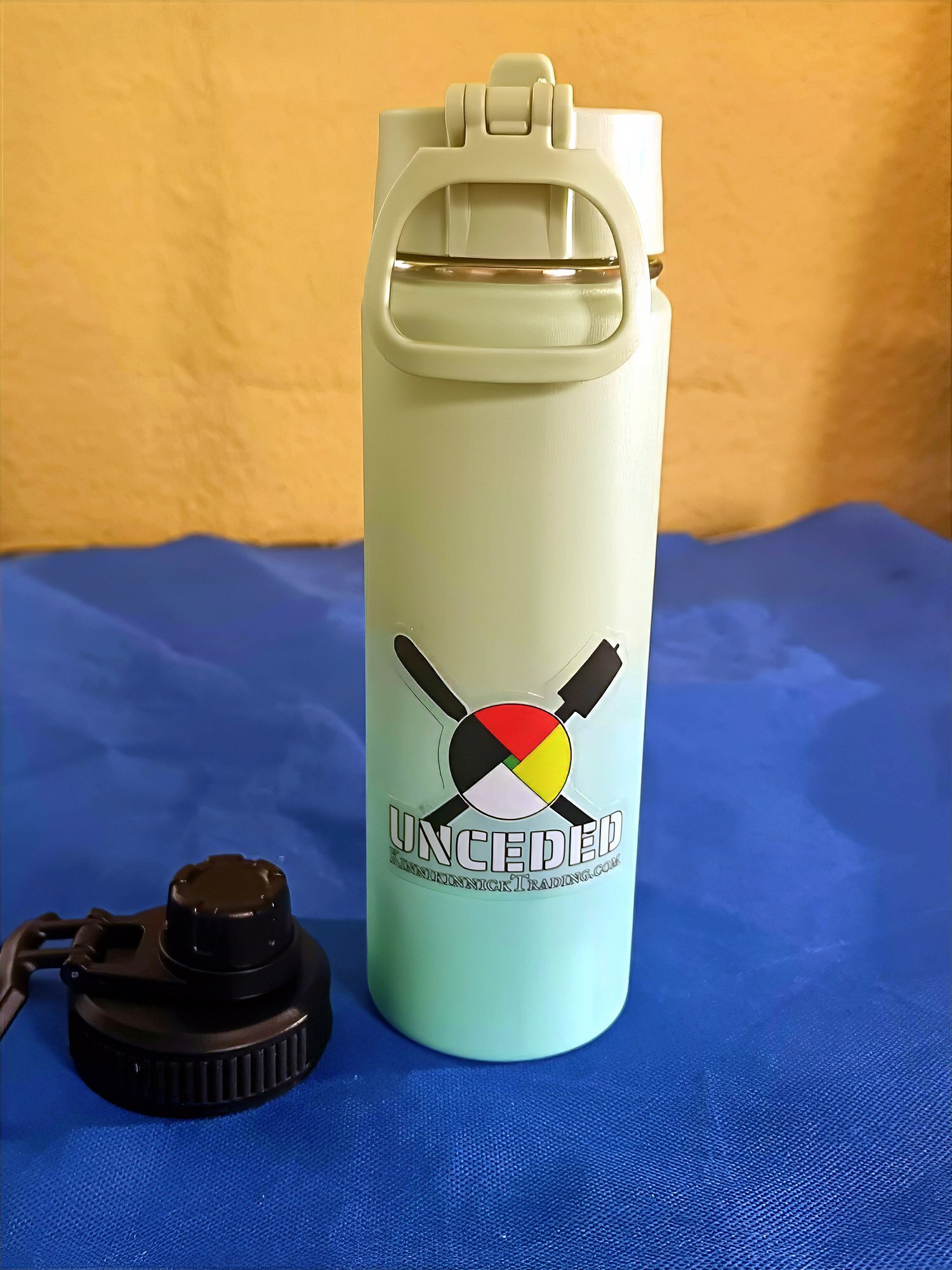 Light green thermos with Uncle Deep logo on a blue surface.