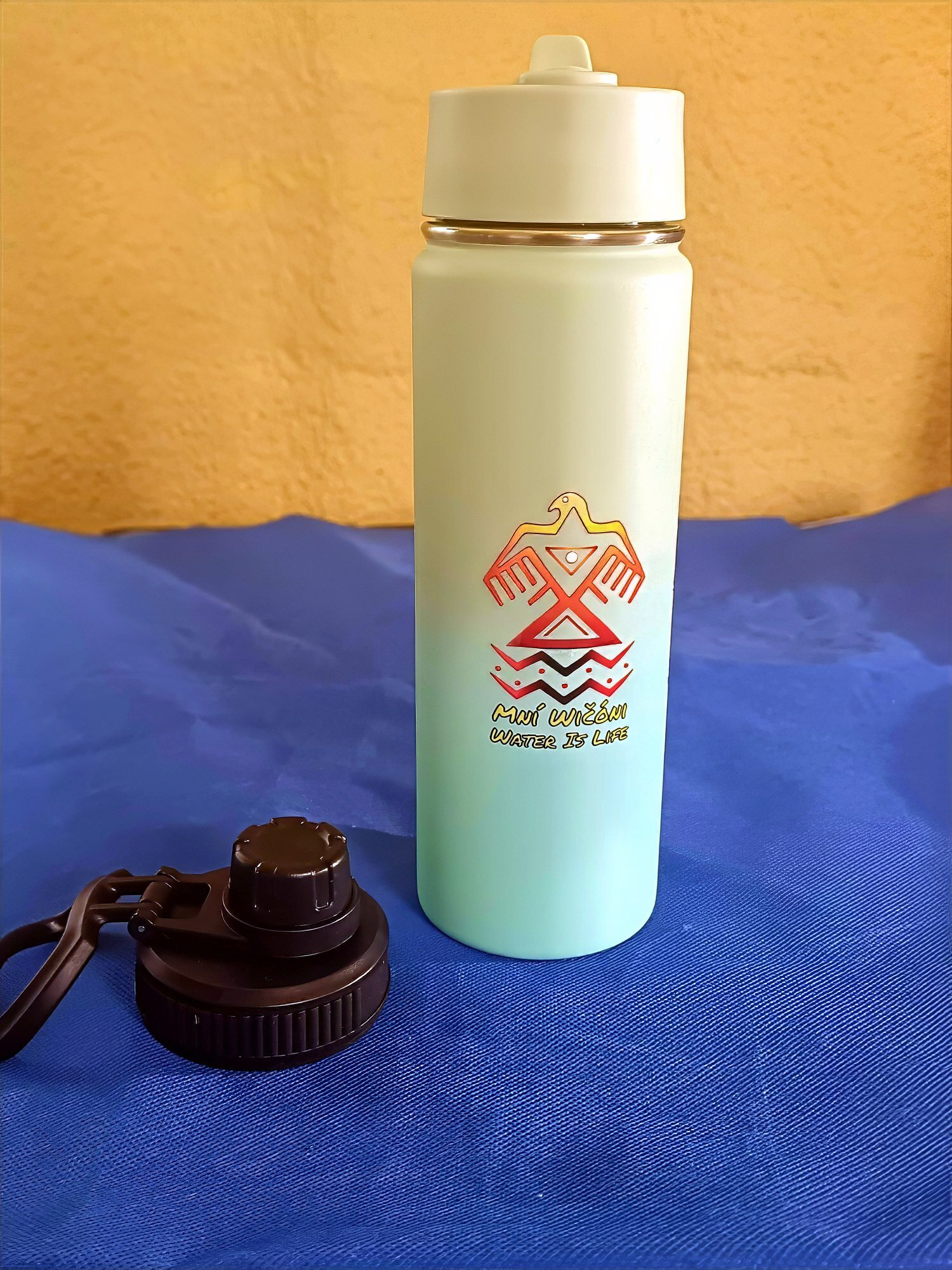 Kinnikinnick Trading Co. branded water bottle on blue surface.